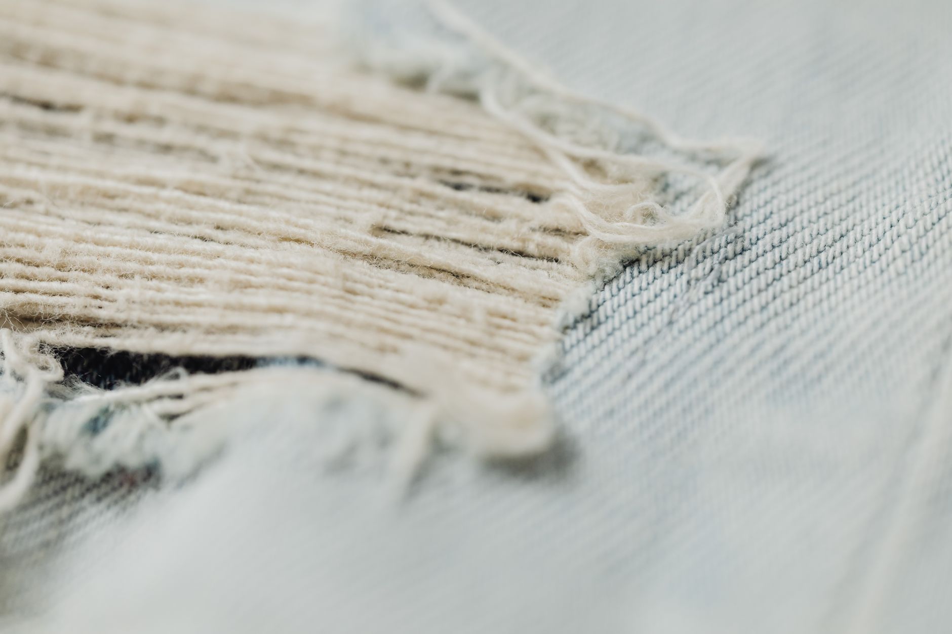 Detailed macro shot showcasing the frayed texture of a denim fabric, highlighting its woven pattern and wear.