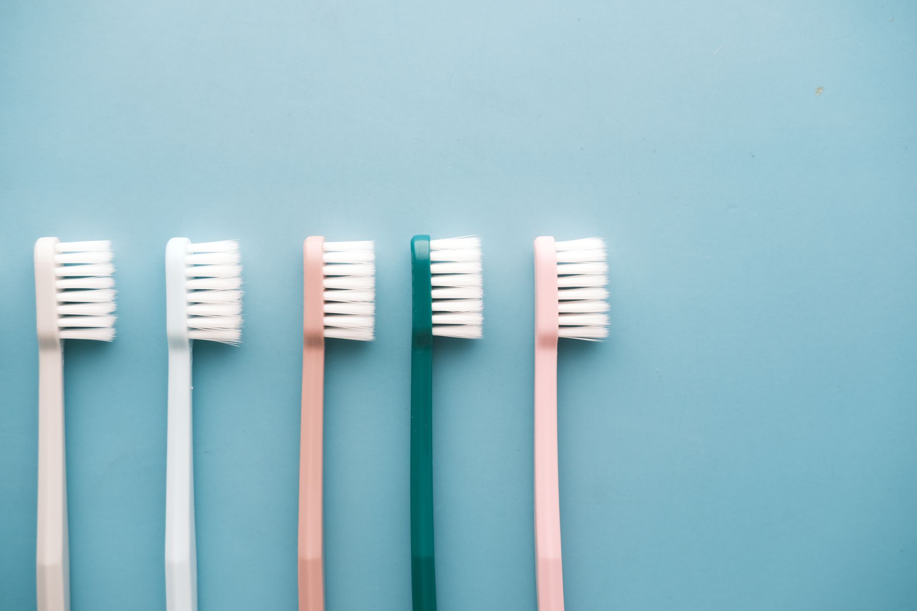 A row of five colorful toothbrushes arranged on a blue background, perfect for dental care themes.
